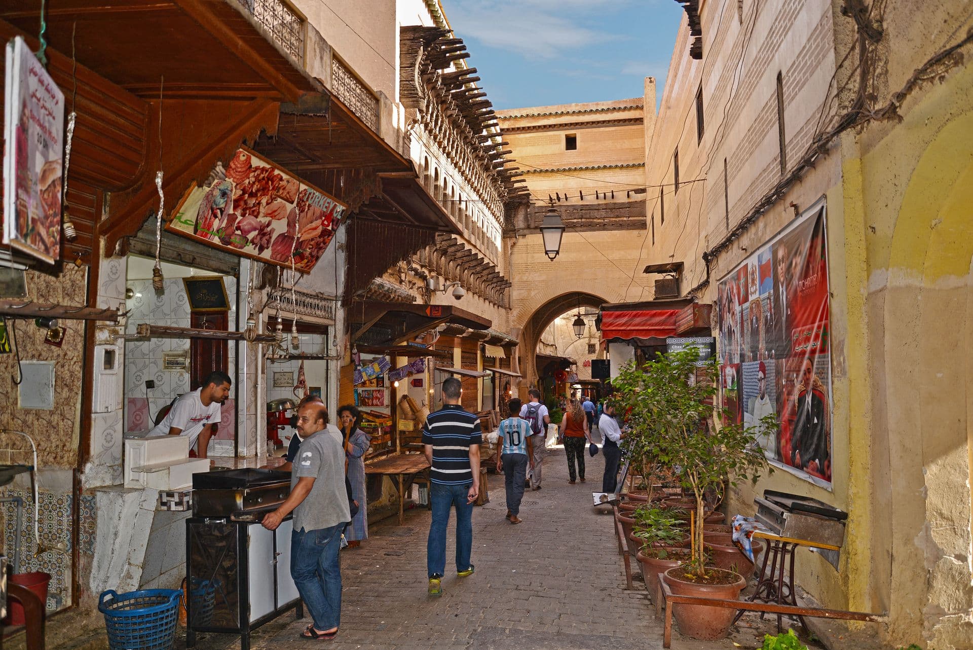 Vibrant street scene in the Medina of Fès, Morocco, with locals and market stalls.