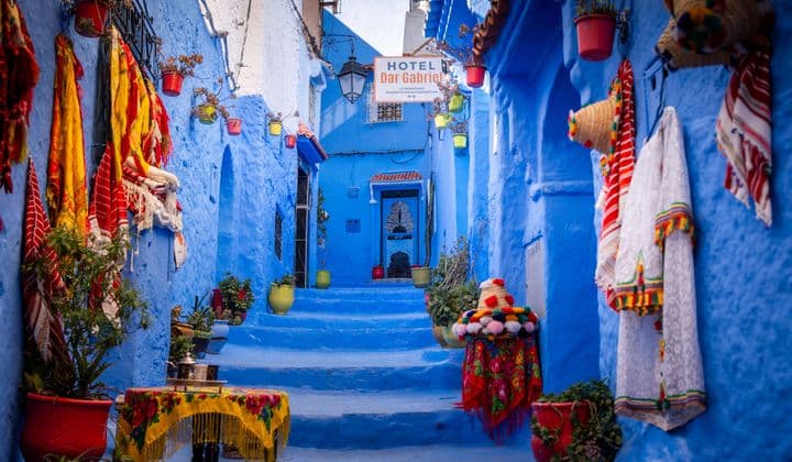 Colorful blue alleyway in the medina of Chefchaouen, Morocco with traditional textiles.